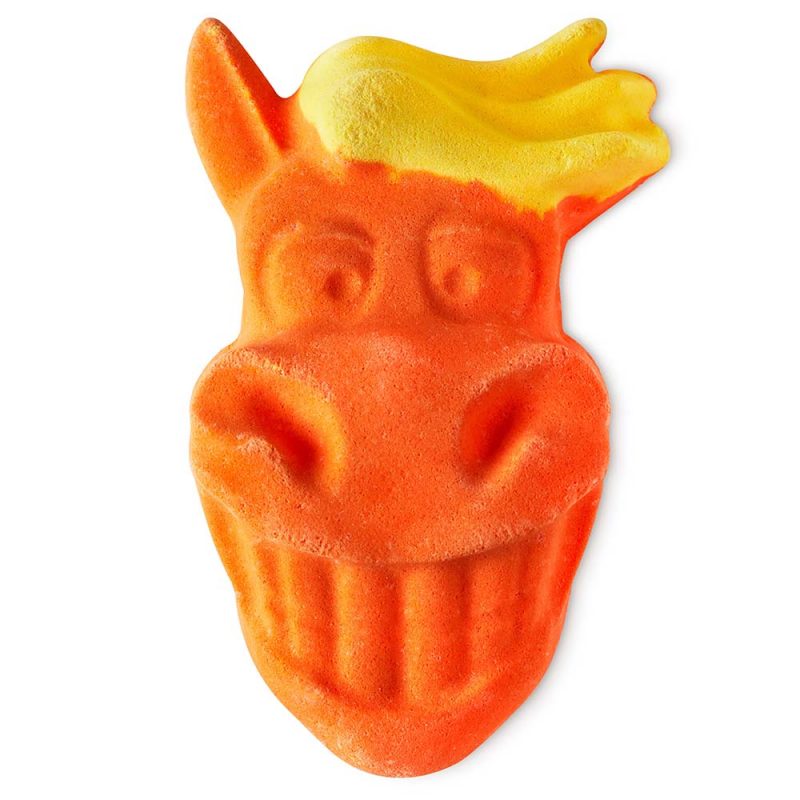 Gift Horse, an orange bath bomb representing the face of a horse with yellow hair, smiling greatly, showing its teeth.